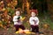 Cute little  twin girls playing with vegetable marrow in autumn park. Autumn activities for children. Halloween and Thanksgiving