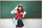 Cute long haired Asian girl Thai people wearing glasses and Japanese school uniforms standing in front of the blackboard