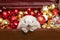 Cute lop-eared rabbit looks out of a chest with red and gold Christmas balls