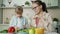 Cute loving daughter helping mother with salad feeding young woman and laughing