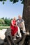 Cute loving retired couple sitting on big tree near beautiful river