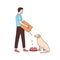 Cute male volunteer feeding stray dog in animal shelter or pound. Young man giving food to homeless or abandoned doggy