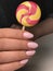 Cute manicured nails with lollipop in hand