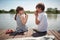 Cute minor couple sitting by the river eating watermelon