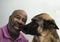 Cute moment between an African American man and his German Shepherd dog who is giving kisses