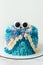 Cute monster cake on the white background. Funny birthday cake with turquoise and blue fluffy cream cheese frosting decorated with