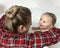 A cute mother is bathing a baby boy in clear water in a bathtub