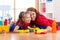 Cute mother and her child daughter dressed like superheroes cleaning the floor and smiling