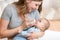 Cute mother at home feeding baby with a milk bottle