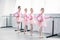 cute multiethnic kids in pink tutu skirts exercising and smiling at camera