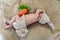 cute newborn baby with a carrot plush toy sleeping on a beige blanket, infant wears knitted rabbit costume