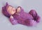 Cute newborn baby girl in purple knitted overall is sleeping peacefully