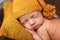 Cute newborn baby in hat on a brown bed and yellow pillow . Sleeping baby on a dark background. Closeup portrait of newborn baby.
