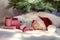 Cute newborn baby sleeping under Christmas tree near red gifts wearing Santa Claus hat