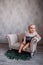 Cute newborn baby on sofa. Infant girl sitting on special little baby furniture
