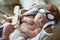 Cute newborn baby wearing aviator hat with toy sleeping in crate