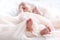 Cute newborn baby in white soft blanket after bath. Closeup of infant foot and blur pastel background