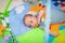 Cute newborn caucasian baby lies on his back on developing mat and looking at toys in selective focus