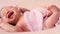 Cute newborn little baby in pink blanket lies on bed
