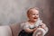 Cute newborn smiling baby on sofa. Infant girl sitting on special little baby furniture