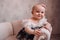 Cute newborn smiling baby on sofa. Infant girl sitting on special little baby furniture