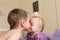 Cute older brother kisses little sister who is swinging on a swing