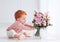 Cute, one-year-old baby girl with delicate flower bouquet
