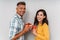 Cute optimistic adult loving couple isolated over grey wall background holding gifts for each other