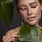 Cute ordinary young woman posing with monstera tropical leafs. Fresh clean skin with flawless texture. Skin care beauty