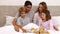 Cute parents and children having breakfast in bed