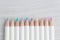 Cute pastel color pencils on light grey wooden background with c