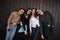 Cute people. Youth stands against black wooden wall. Group of friends spending time together