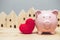 Cute pig smile with red heart on home village background for love community safe house concept