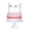Cute pink birthday cake on round pedestal, decorated with blue striped picks and string with colorful paper bunting.