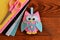 Cute pink and blue owl toy, colored felt sheets, scissors on a wooden table. Fabric owl embellishment
