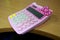 A cute pink calculator for calculating tools for children and adults is on the table