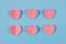 Cute pink paper hearts arranged in two rows on pastel blue background