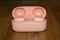 Cute pink wireless Airdopes case on a wooden background