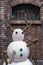 Cute plastic snowman display in front of red brick wall