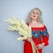 Cute plump girl from the village in a red summer sundress with a sheaf of wheat in her hands on white studio solid background