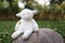 a cute plush lamb toy sitting on a rock