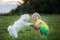 Cute preschool child, blond boy with pink stripes in his hair, taking pictures with his cute maltese dog in the park