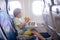 Cute preschool child, flying on a long distant flight, eating burger in the airplane