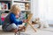 Cute preschool child, playing with abacus at home, little pet dog playing around