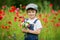 Cute preschool child in poppy field, holding a bouquet of wild f