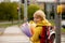 Cute preschool child, waiting on a red light to cross the street, caring bouquets of flowers for teachers, going to preschool