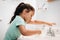 Cute preschool girl practicing good hygiene using the bathroom sink as she washes up