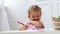 Cute preschool girl sitting by the white table focused on drawing something.