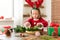 Cute preschooler girl dressed in reindeer costume wearing reindeer antlers making christmas wreath in living room. Christmas decor