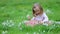 Cute preschooler girl in pink tutu skirt sitting in the grass with many snowdrop flowers